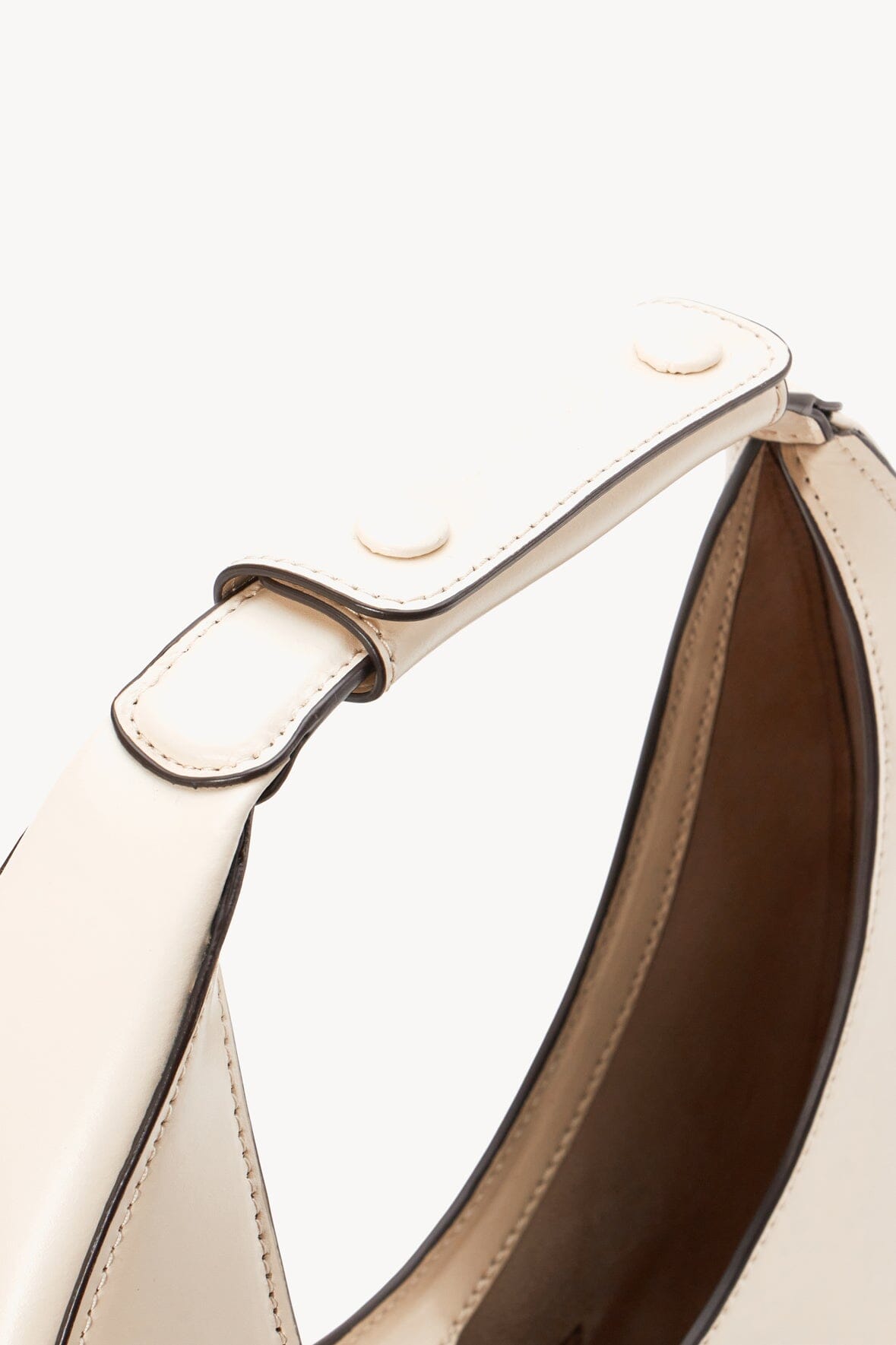 Cream handle ends with stitched ring attachments and small hardware tabs