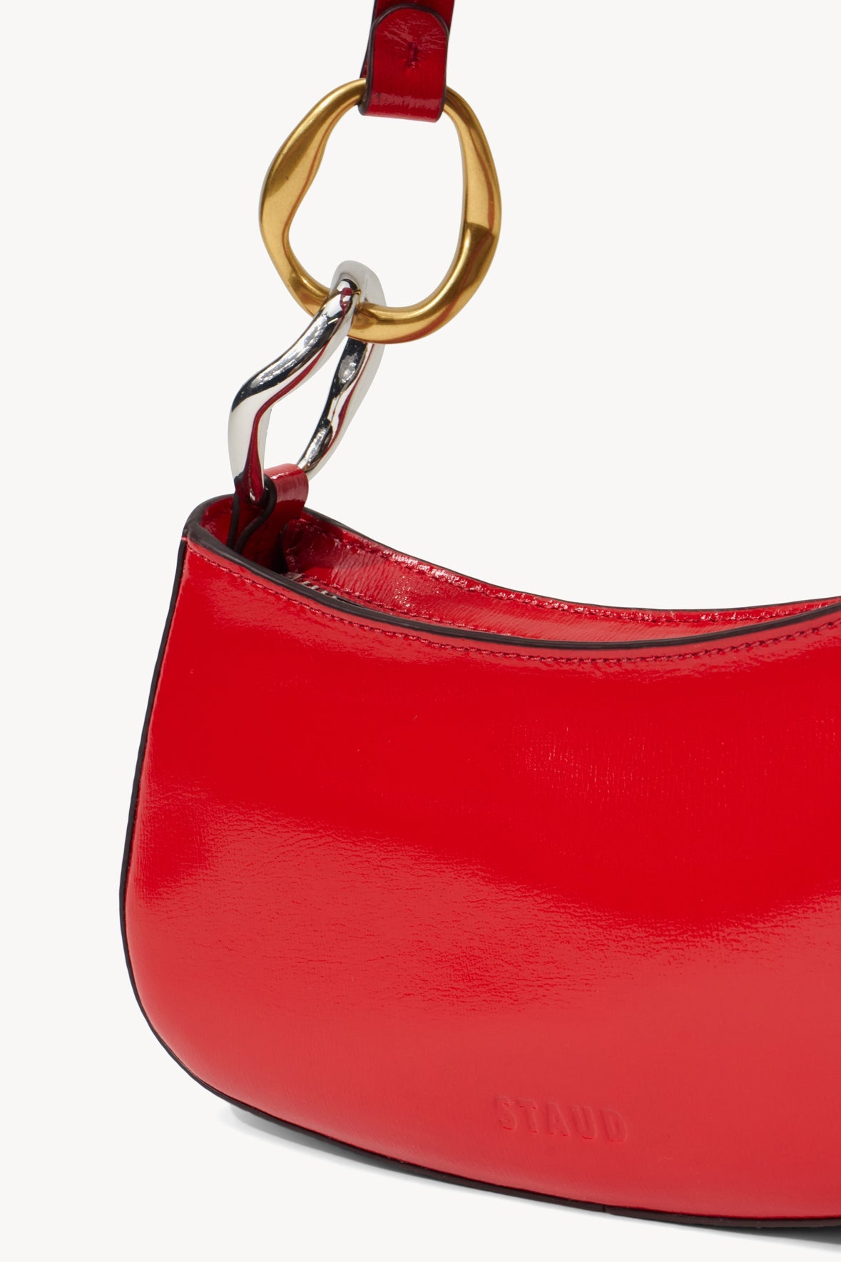 Close-up of red bag top with gold ring and leather handle