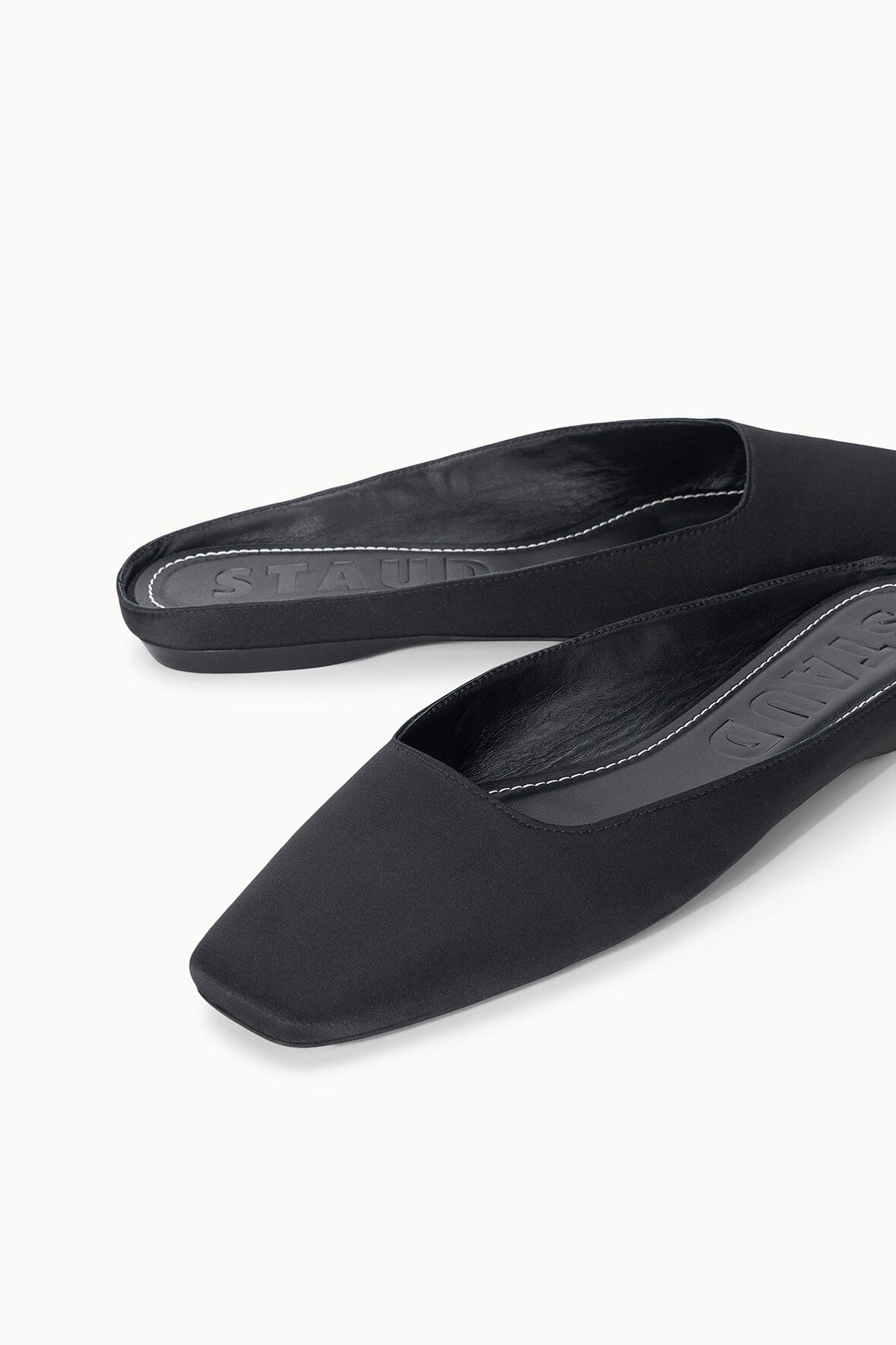 Black flat mule close-up showing stitched topline and interior lining