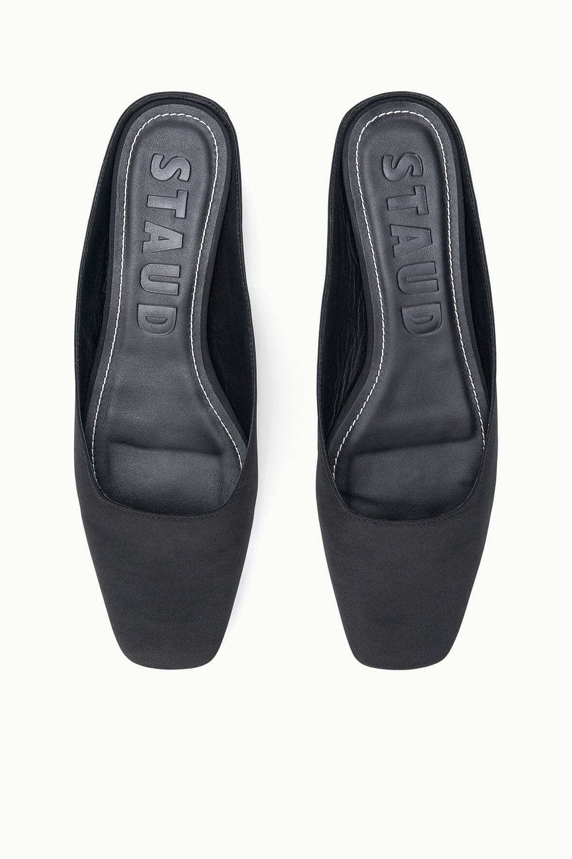 Black flat mule pair with embossed “STUDIO” text on footbed