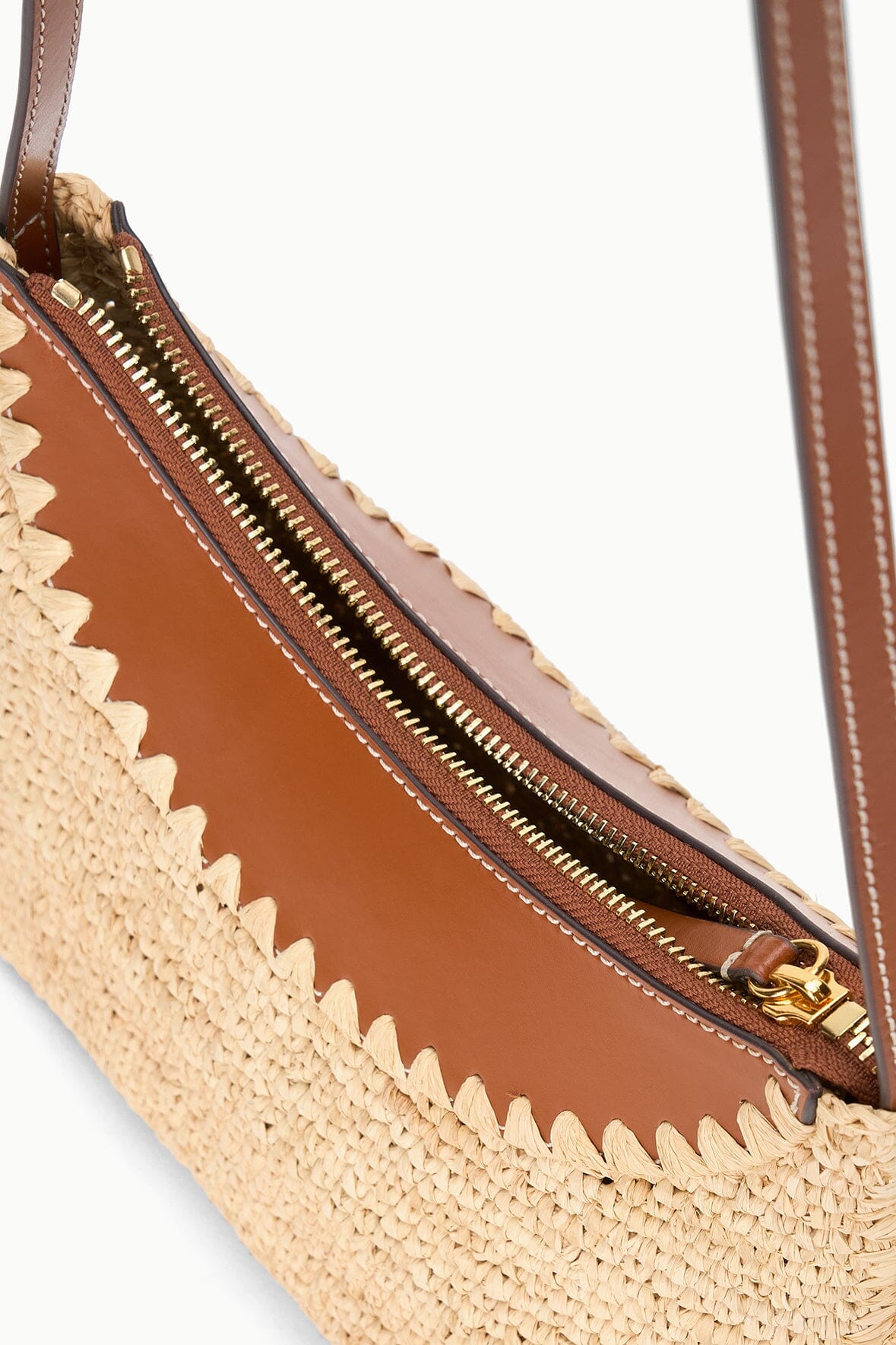 Raffia hobo bag interior with brown lining, gold zipper, and leather shoulder strap
