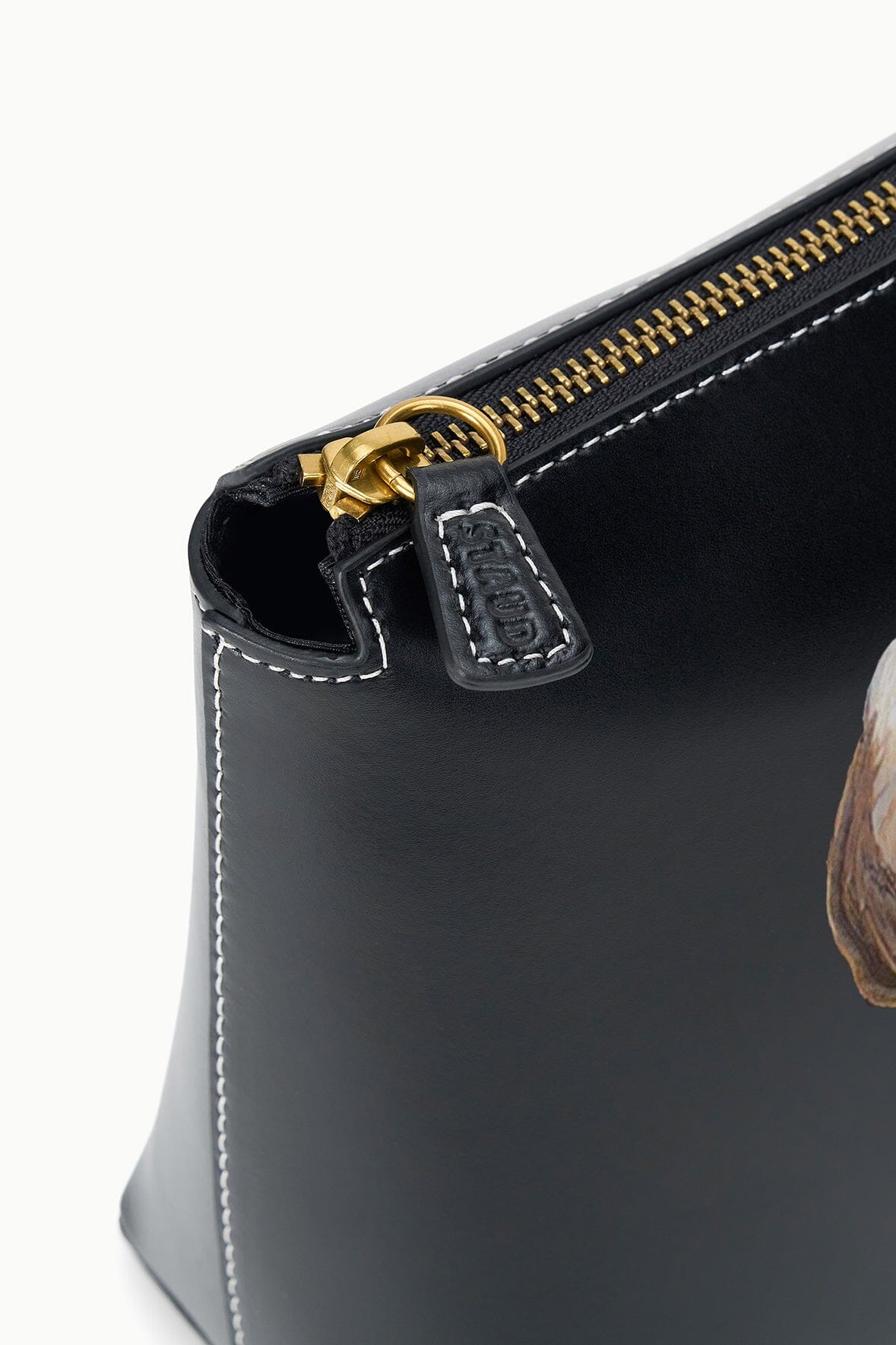 Black pet pouch detail with gold zipper and stitched trim