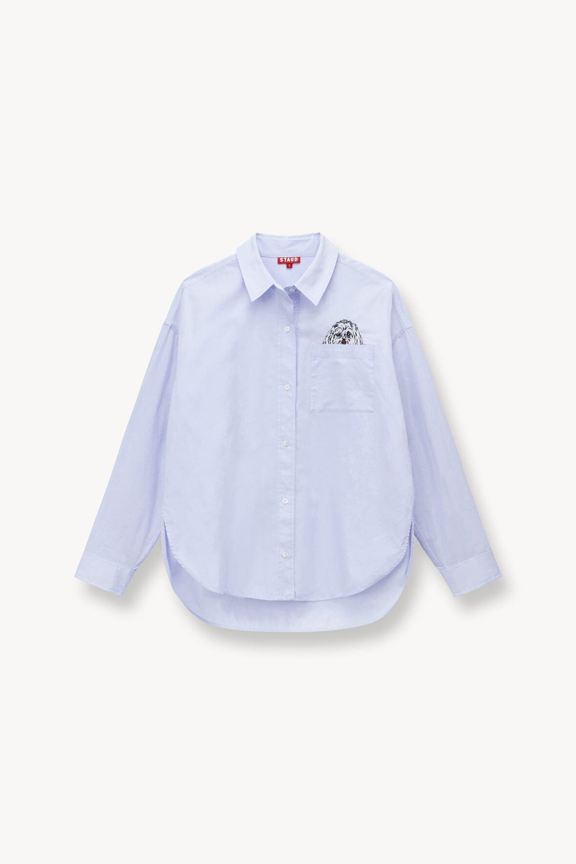 Folded light blue oversized button-up shirt with pointed collar and chest logo patch