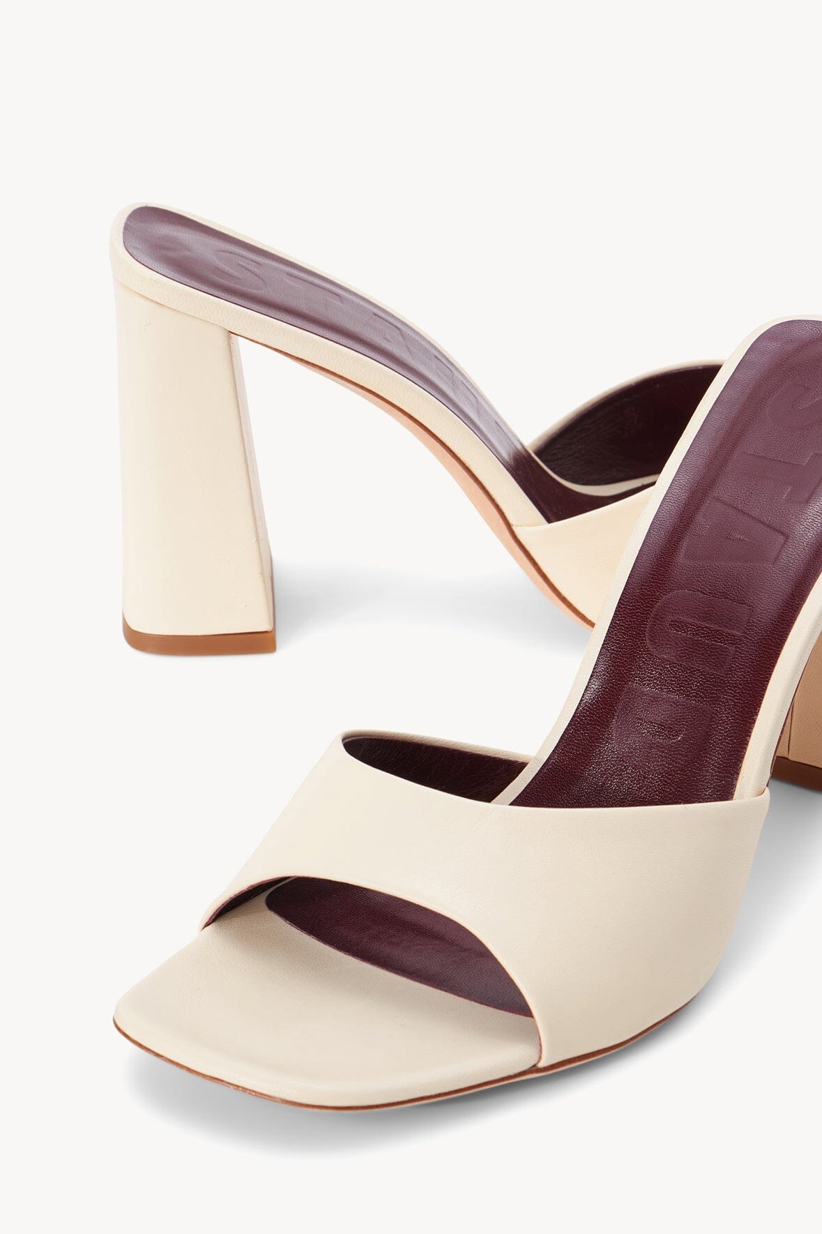 Cream heeled slide sandal with open toe and dark footbed