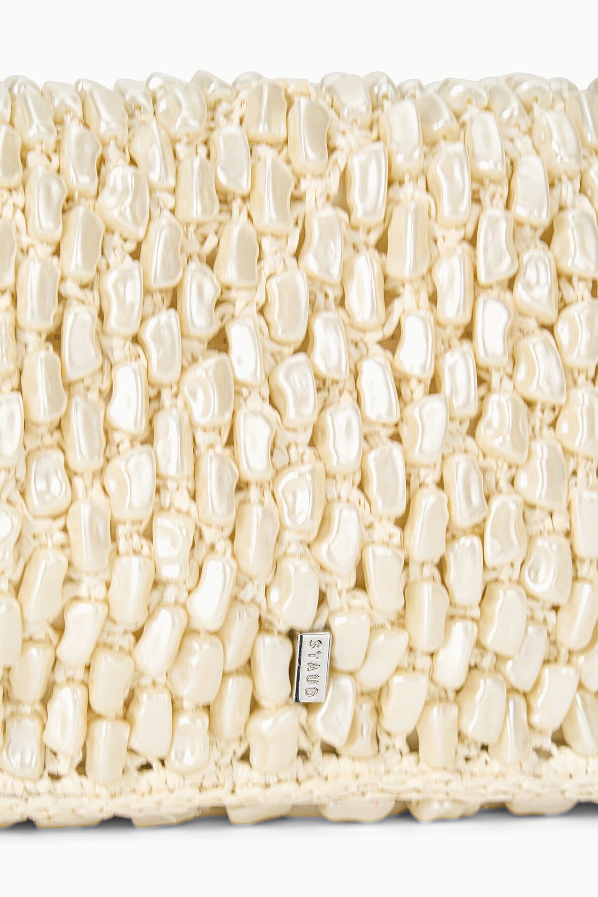 Cream woven bag front panel with small rectangular brand tag
