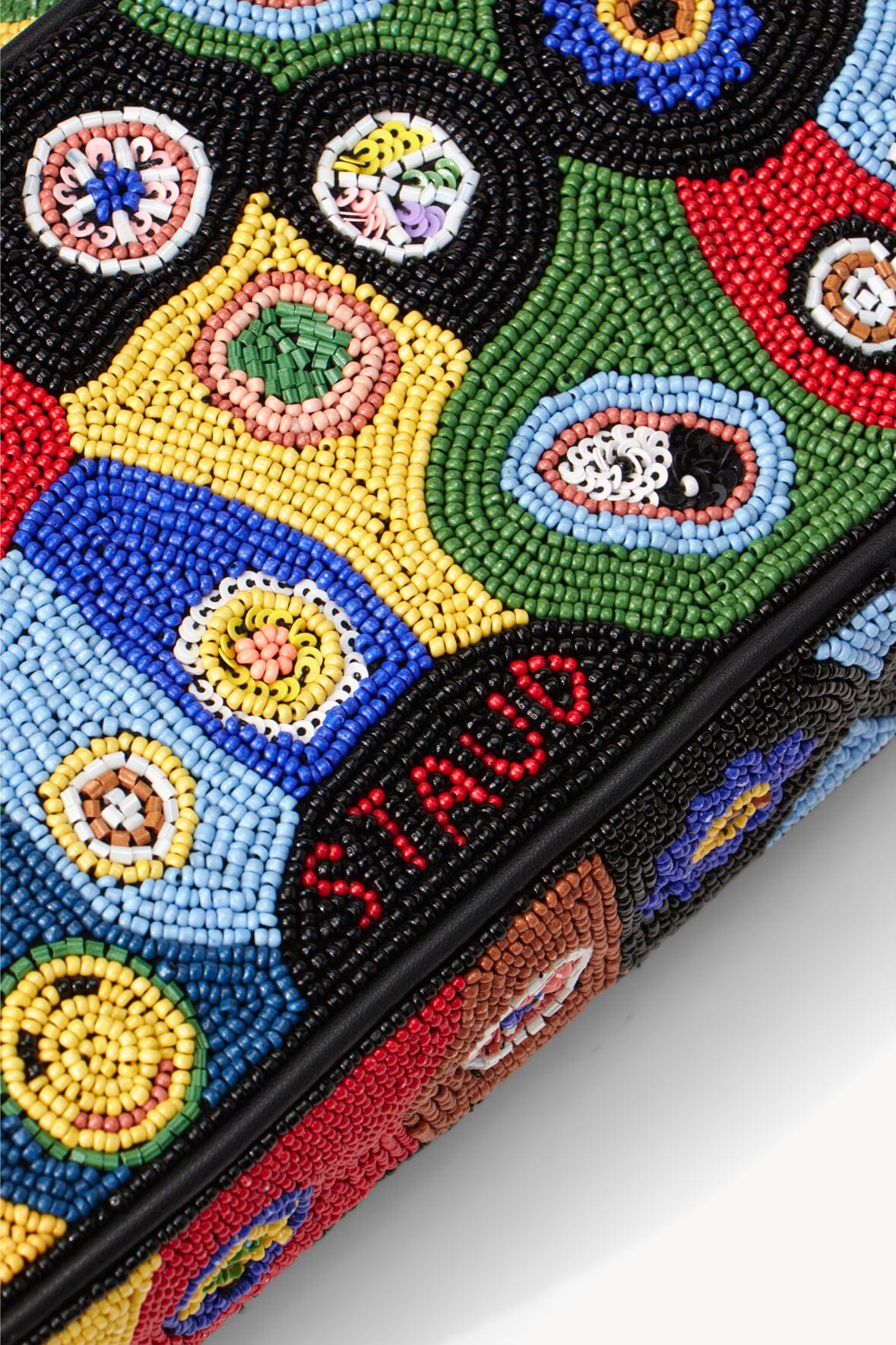 Beaded bag edge with multicolor circular motifs and red letter detail.