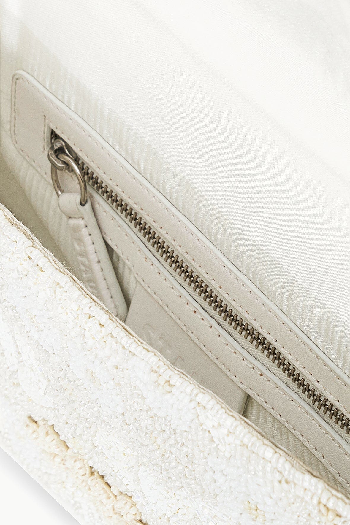 Beaded handbag interior view with zipper track and light lining.