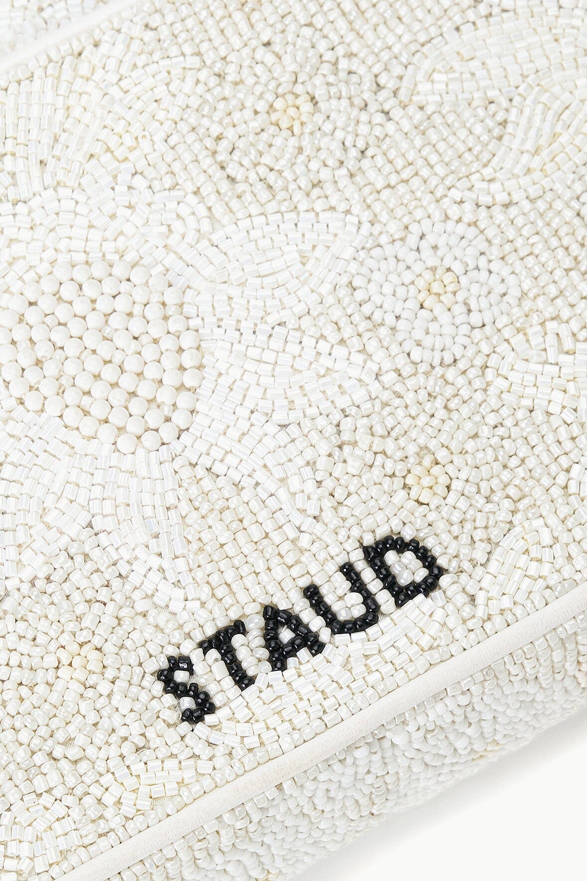 White beaded handbag with black 'STAUD' beaded logo and zipper trim.