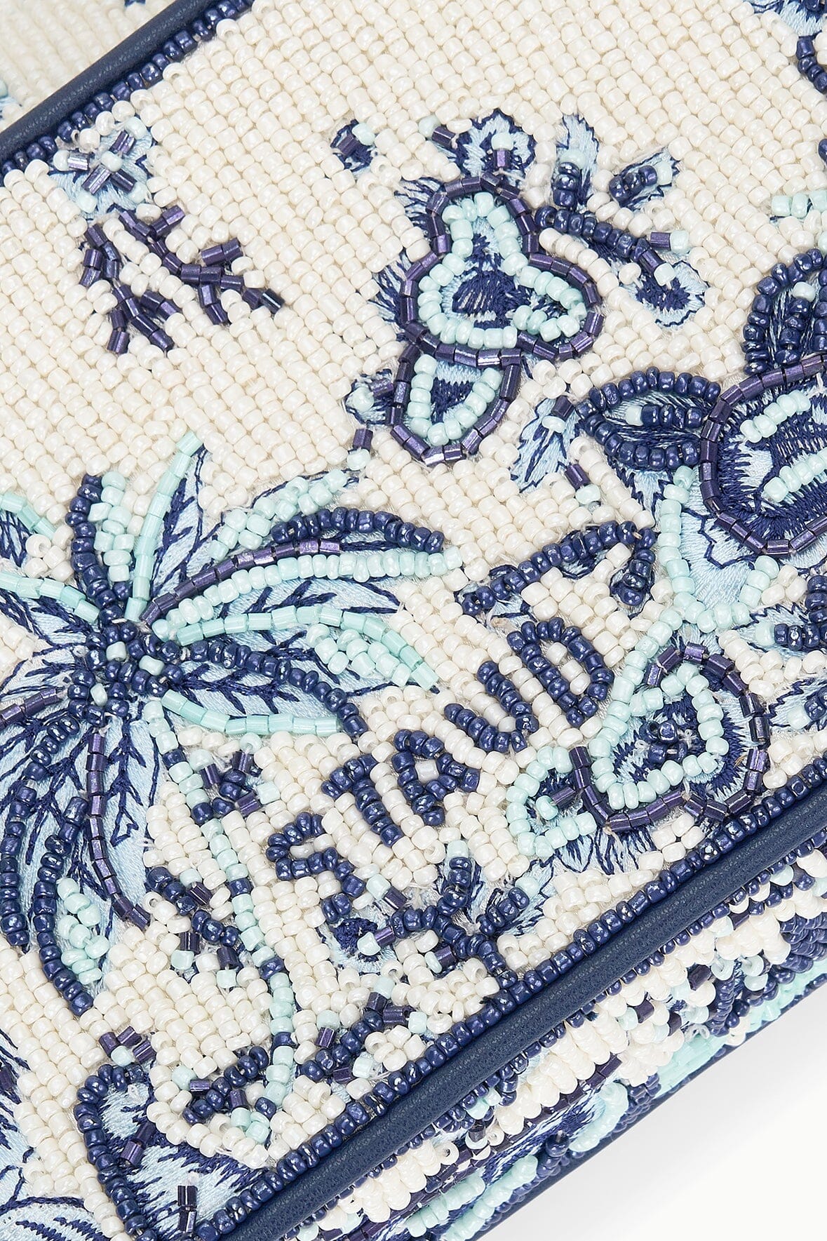 Close-up of cream beaded bag surface with blue toile-style embroidery