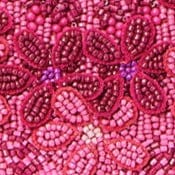 Pink bead embroidery close-up with floral motifs and glossy bead texture.