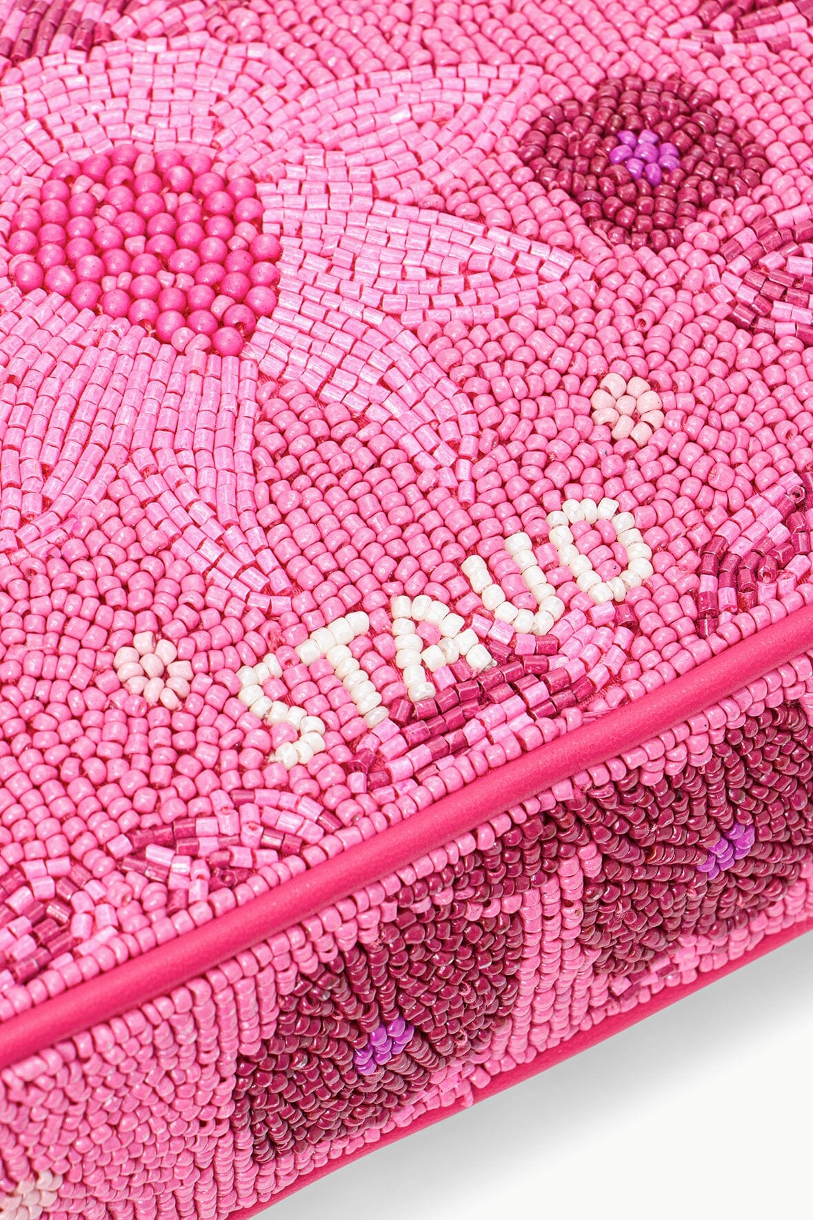 Close-up of pink beaded surface with raised floral pattern and bead texture.