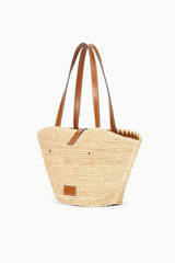 Natural tan woven tote bag with tan leather handles and small front patch