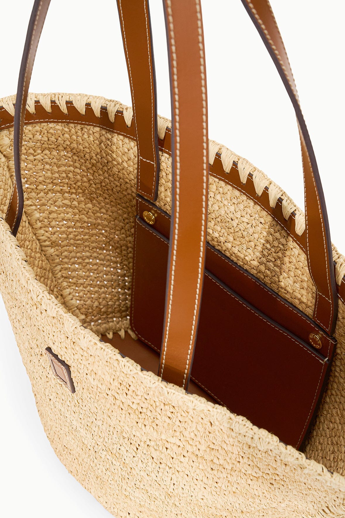 Natural tan woven tote bag interior with brown leather lining and side pocket