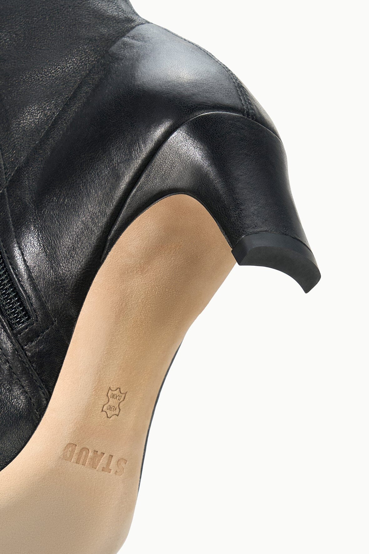 Close-up of black leather ankle boot upper with side seam and heel detail.