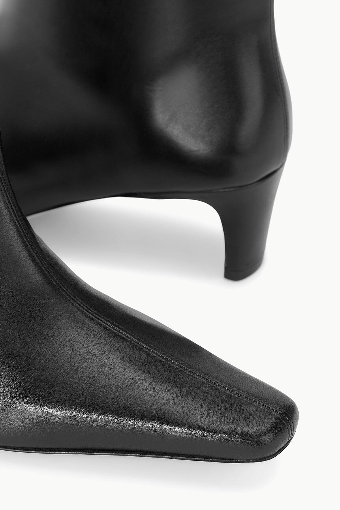 Black leather ankle boot close-up with side stitching and low heel