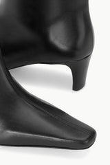 Black leather ankle boot close-up with side stitching and low heel