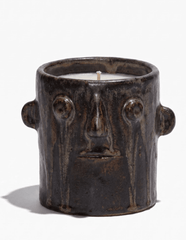 Brown ceramic candle holder with face motif and small wick in open top