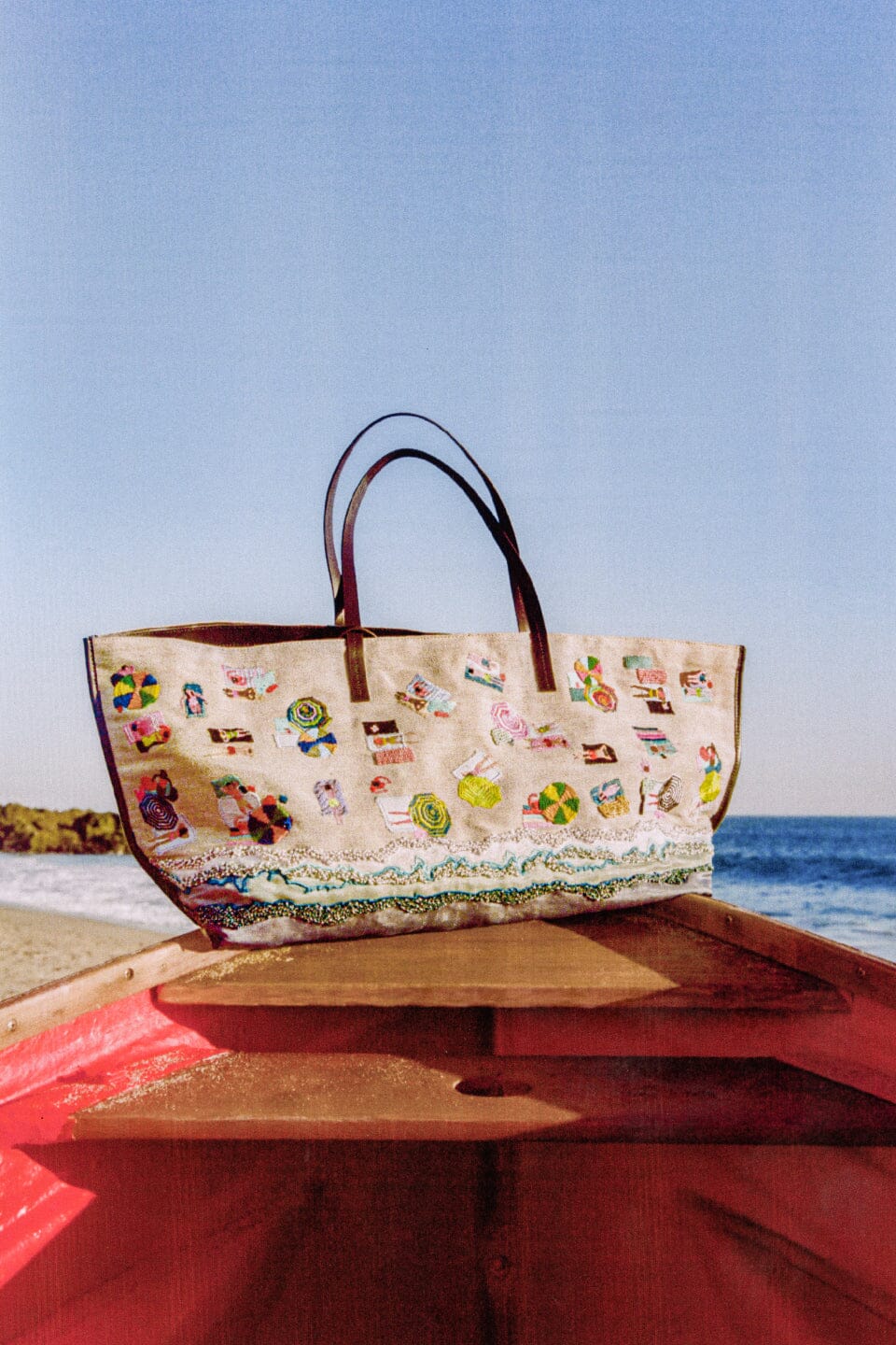 Printed large beach tote on a wooden surface, beach artwork with blue bottom and black handles