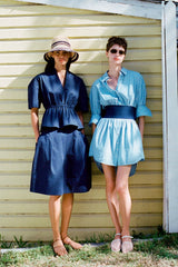 Two models wearing striped straw bucket hats with navy banding