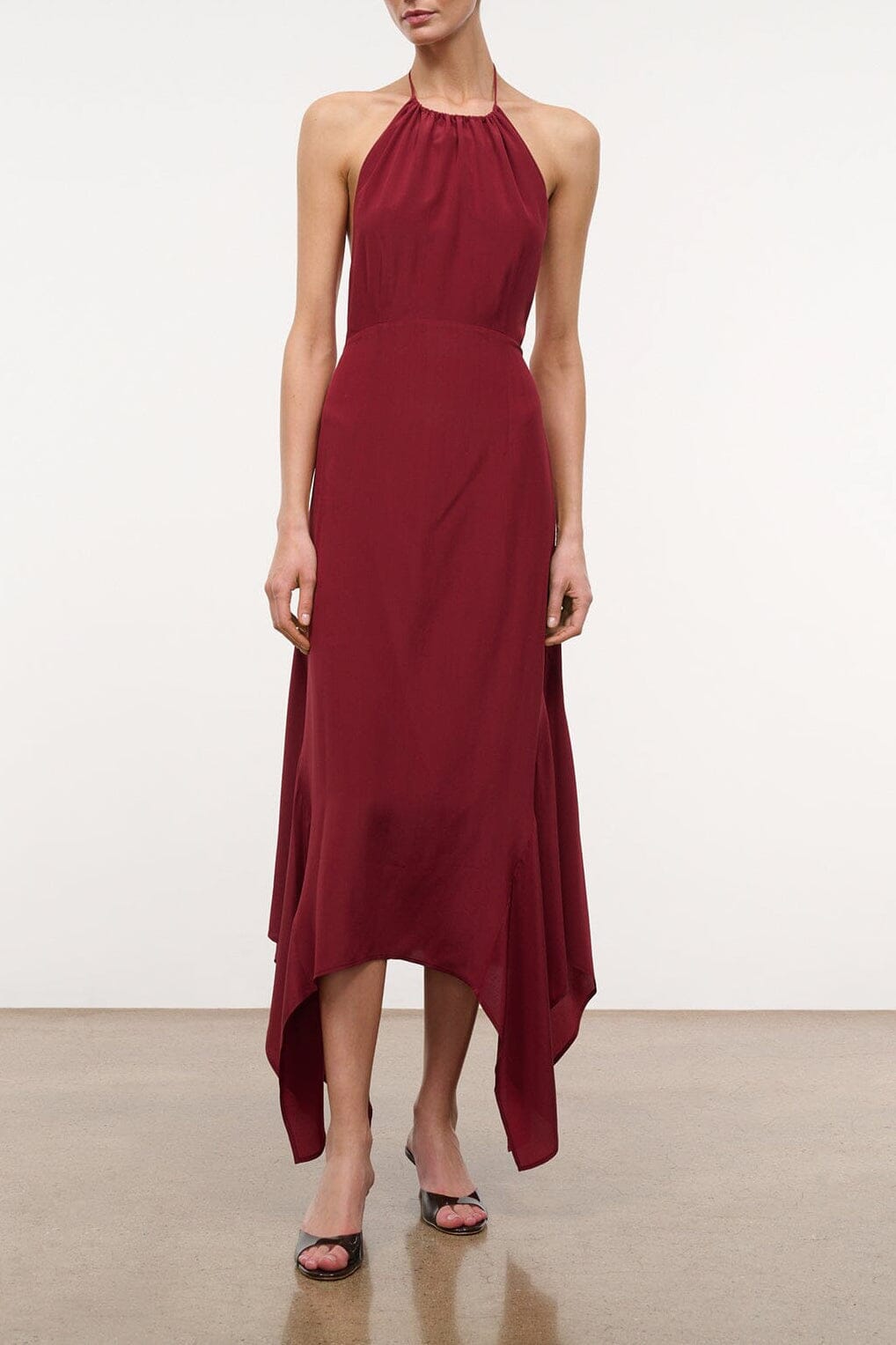 Burgundy silk halter dress with sleeveless cut and draped asymmetrical hem