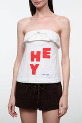 Strapless white bandeau top with ruffled edge and bold red “HEY” print