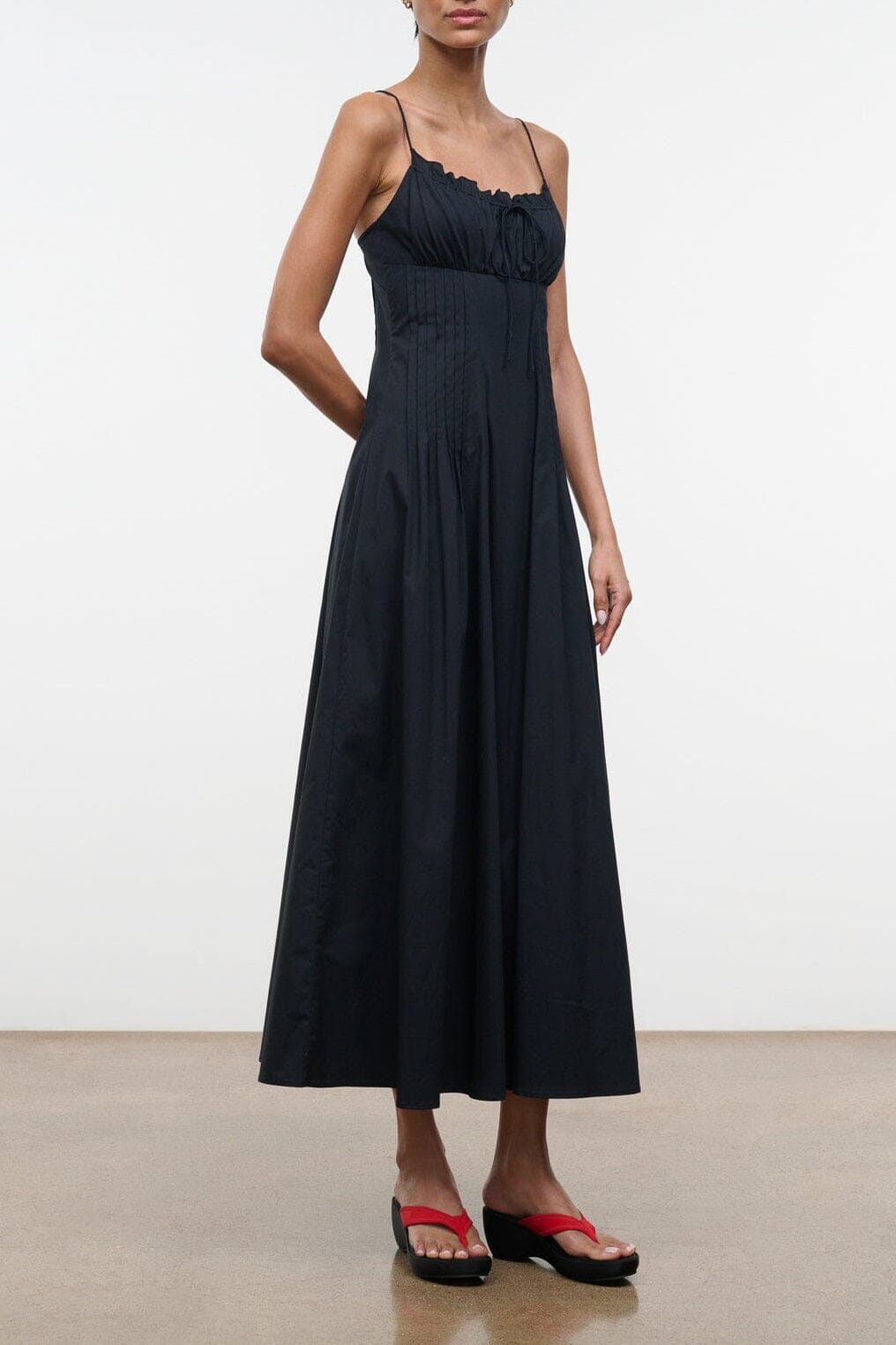 Black sleeveless dress with scalloped neckline, spaghetti straps, gathered bodice and skirt