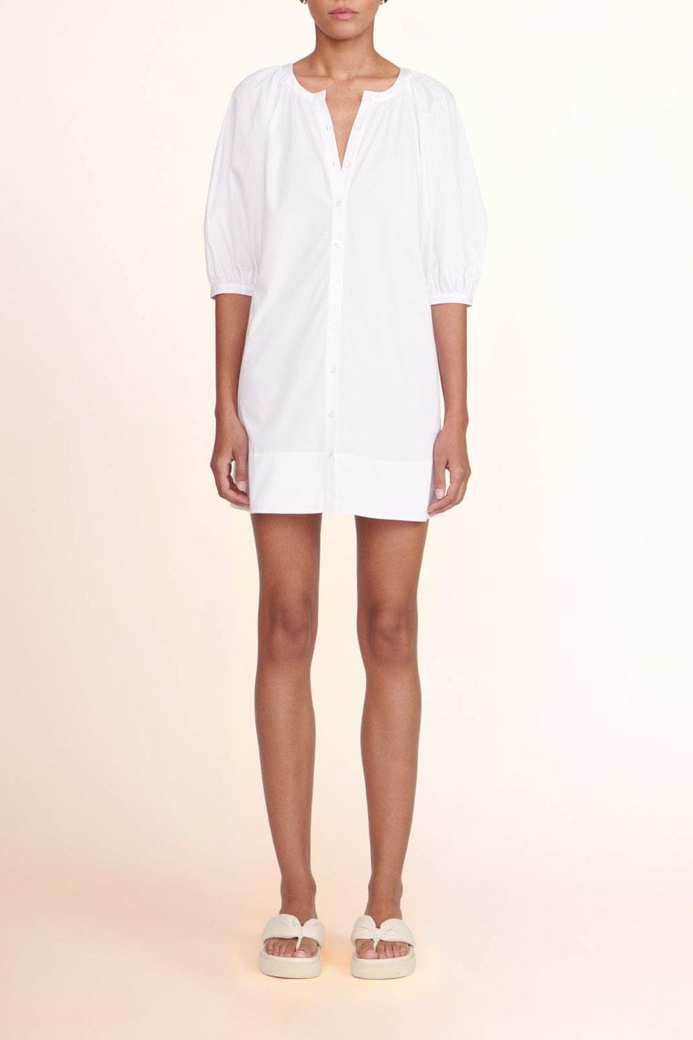 White mini shirt dress with V-neck, button front, and three-quarter puff sleeves