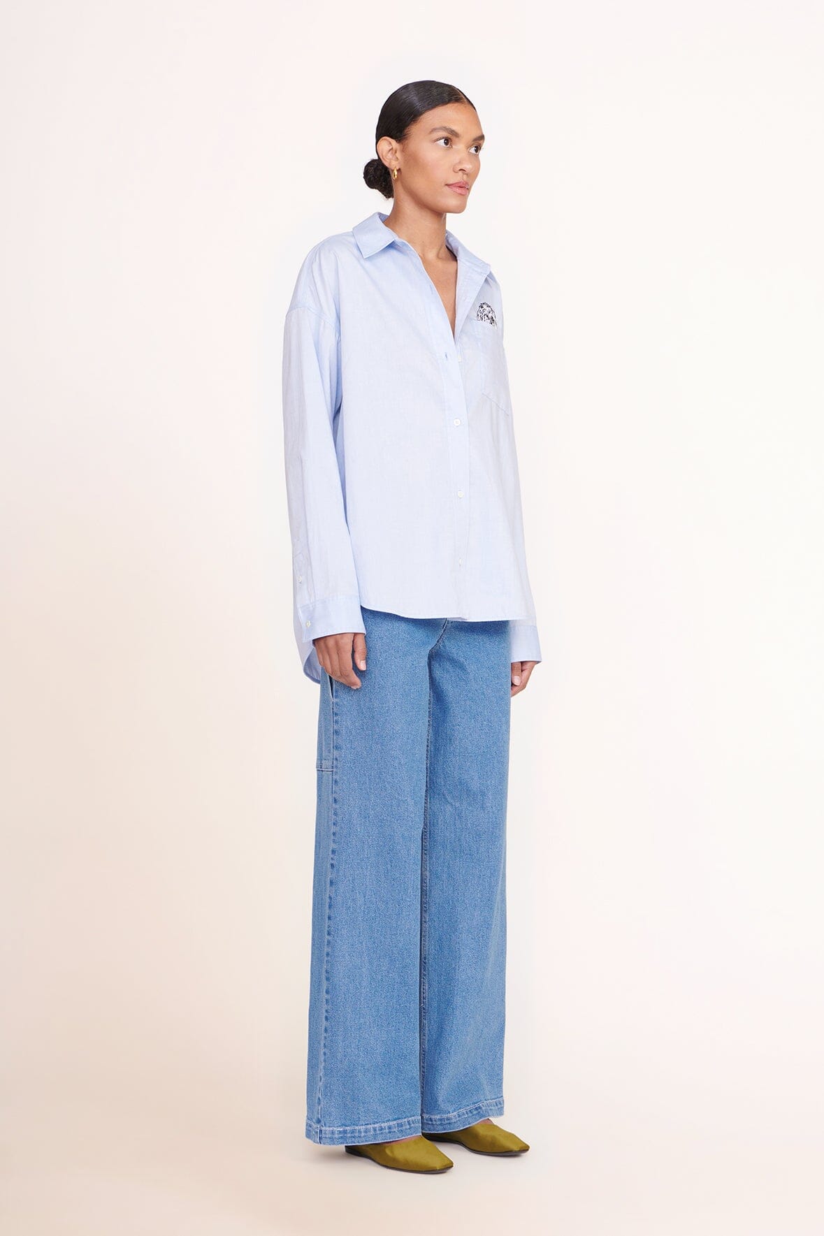 Light blue oversized button-up shirt, pointed collar, front button placket, chest logo patch