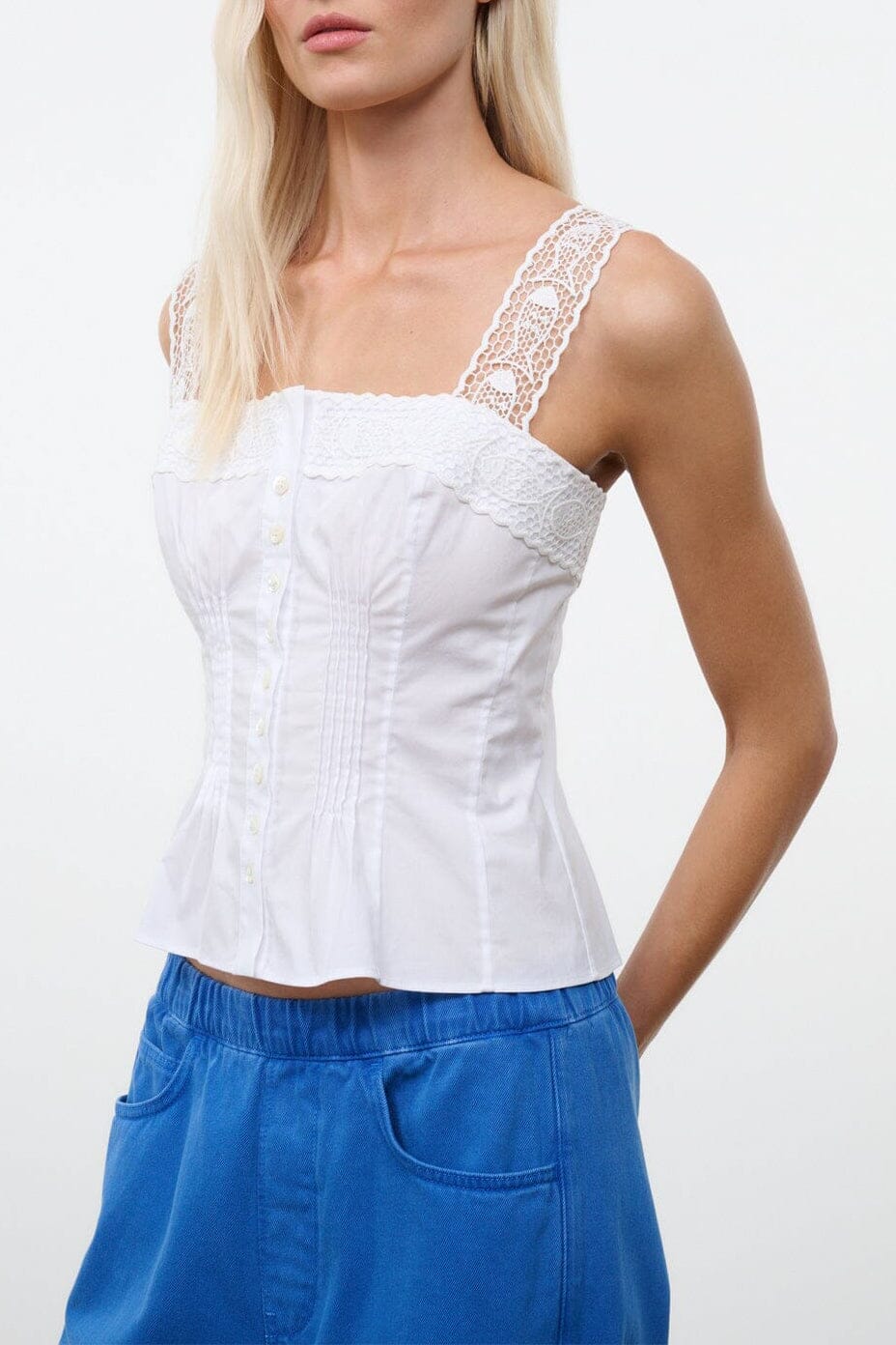 White sleeveless corset-style top with lace trim and button front